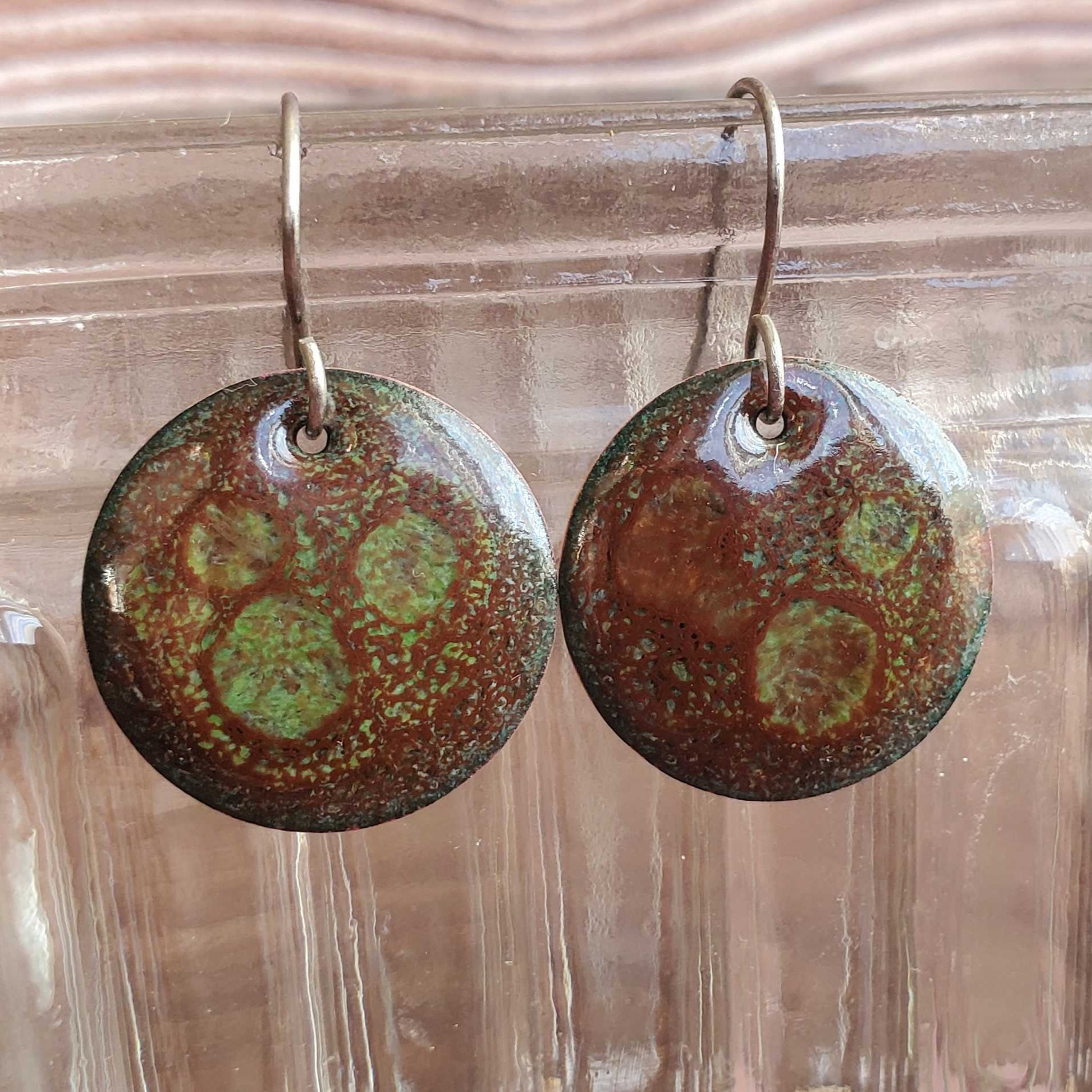 Pair of round copper and glass earrings with brown and green patterns 