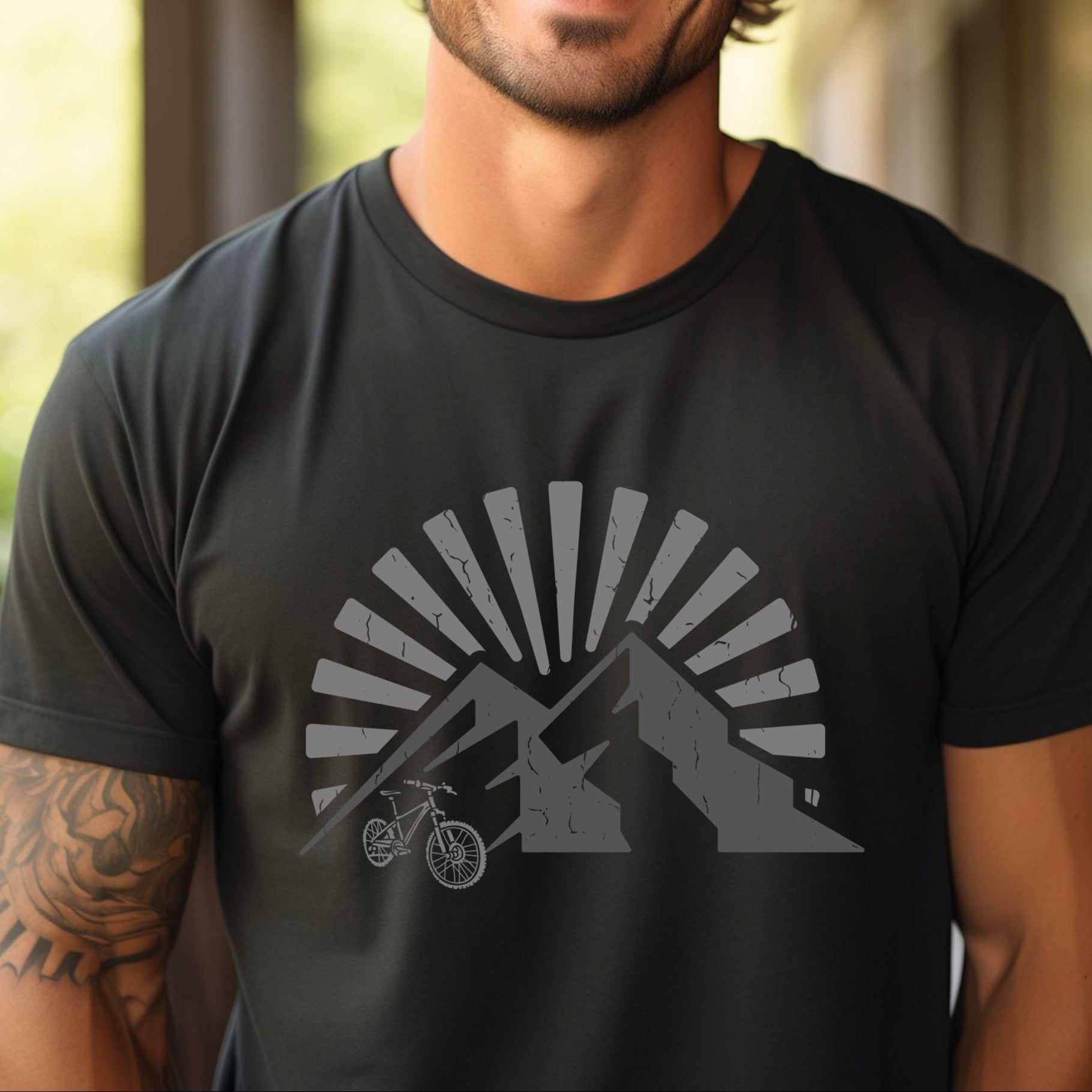 Man wearing a black t-shirt with a mountain and bike graphic and sunrise  or sunset background